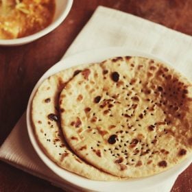 butter naan served on a white plate with a bowl of curry kept on the top left side and text layover.