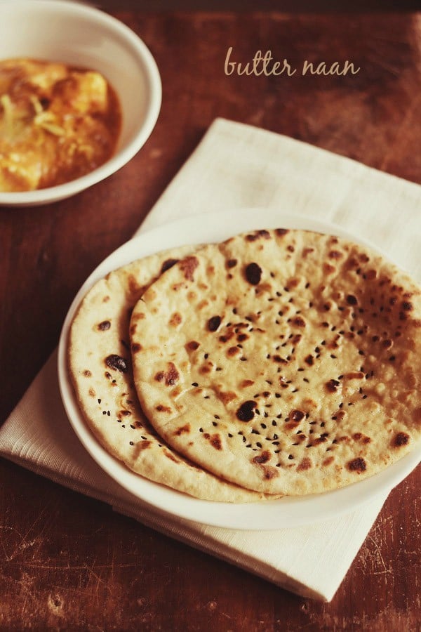 butter naan served on a white plate with a bowl of curry kept on the top left side and text layover.