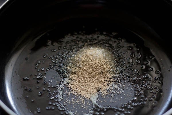 yeast and sugar added in a bowl for making dough for butter naan recipe. 