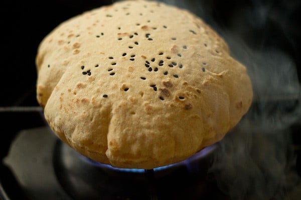 butter naan sprinkled with nigella seeds, getting puffed on direct flame. 