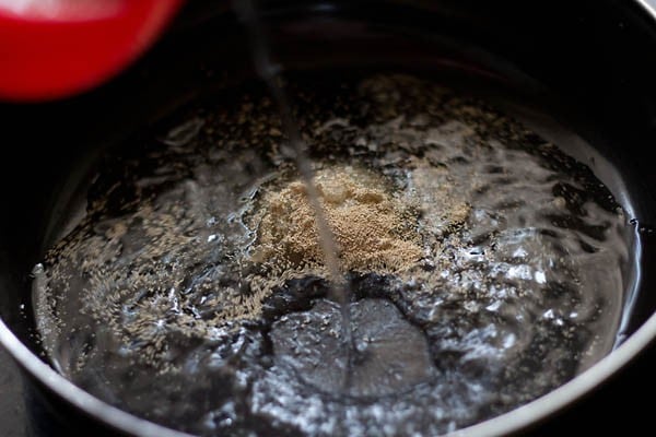 adding water to the bowl for making dough for butter naan recipe. 