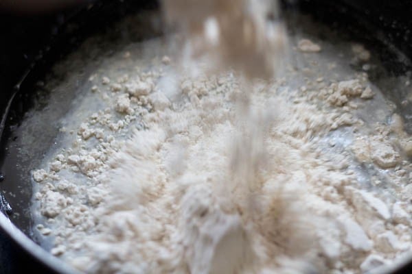 adding whole wheat flour to the bowl for making dough for butter naan recipe. 