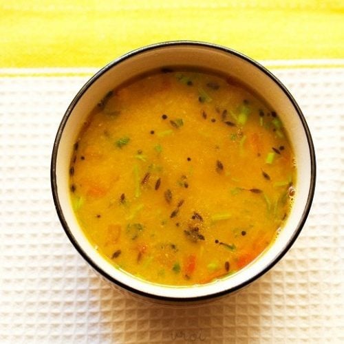 gujarati dal in a black rimmed bowl on a white and yellow linen napkin.