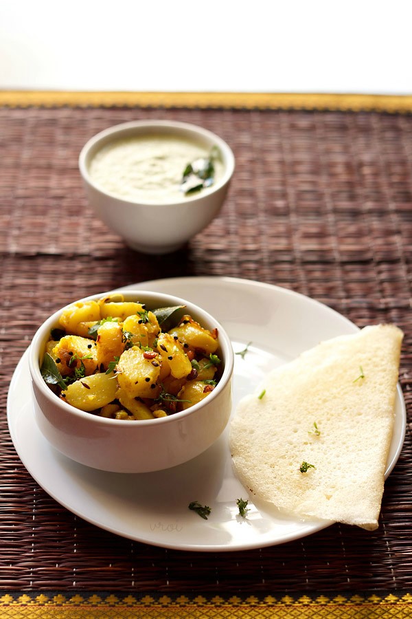 aloo masala for dosa served in a bowl with a dosa and a bowl of coconut chutney kept on the top side. 