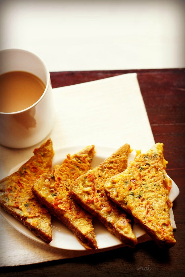 besan bread toast served on a white plate with a cup of tea kept on the left side. 