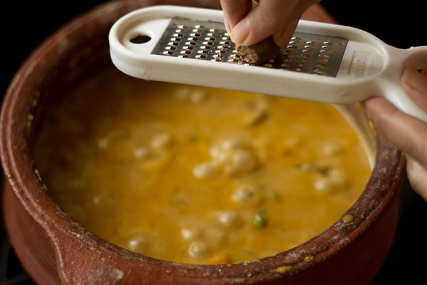 grating nutmeg into the veg handi gravy. 