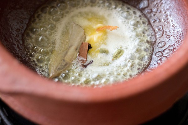 sautéing whole spices in melted butter in handi. 