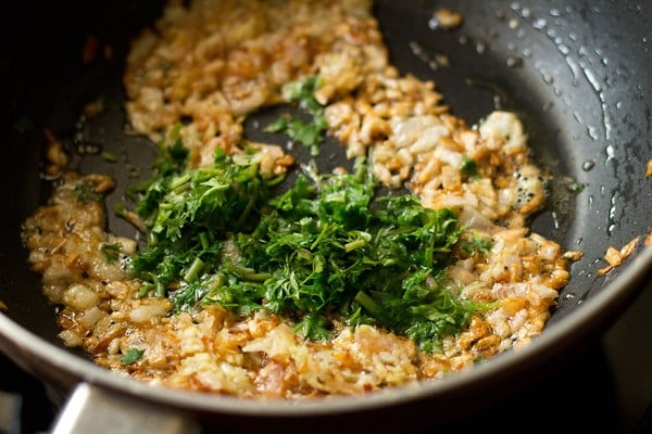 adding chopped coriander leaves to onions