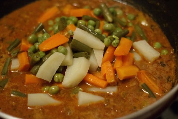 adding steamed vegetables to veg kolhapuri 