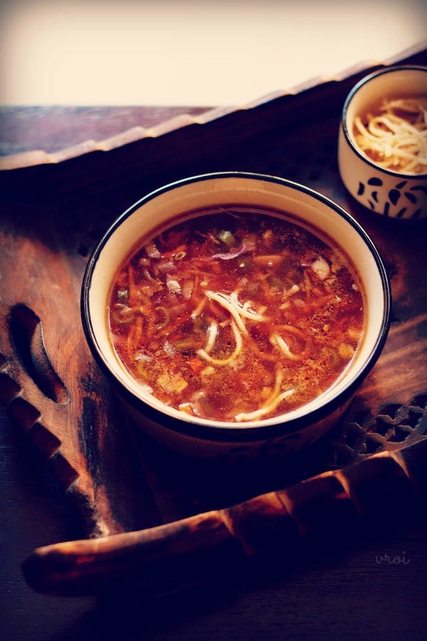 veg manchow soup in a blue and white bowl on a wooden serving tray