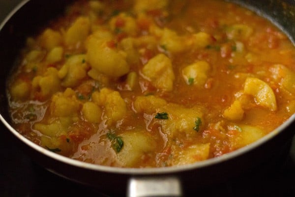 stirring the ingredients in the aloo rasedar. 