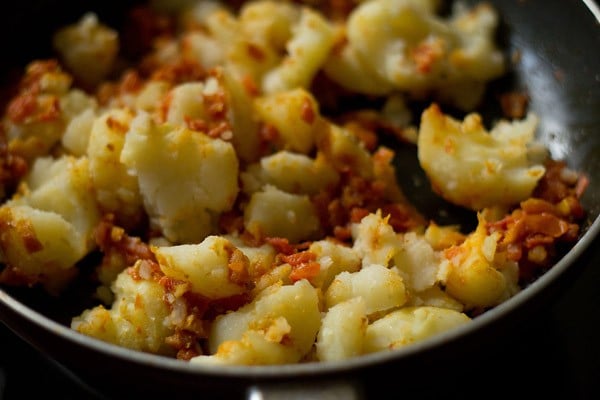 adding rumbled potatoes to the tomatoes and sautéing. 