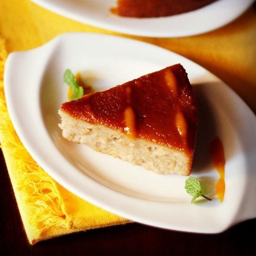 thick triangular slice of bread pudding on white plate.