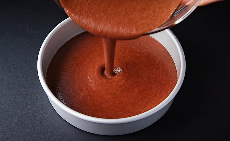 pouring the healthy vegan chocolate cake batter in the cake pan