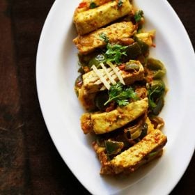 paneer khurchan garnished with coriander leaves, ginger juliennes and served on a white plate.