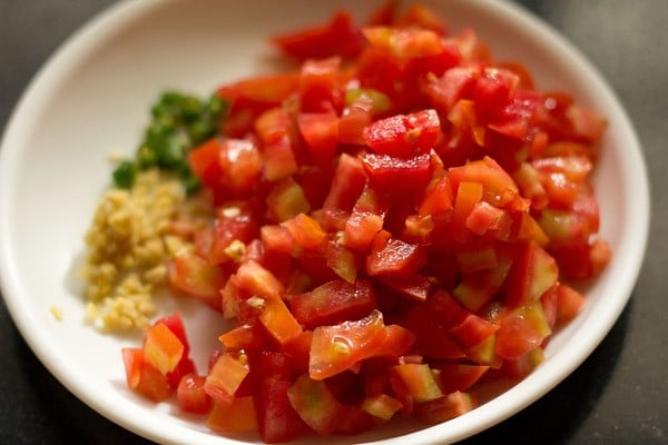 chopped tomatoes, chopped ginger and chopped green chilies for making sev tamatar sabji. 