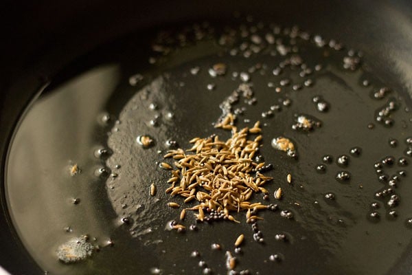 cumin seeds added to the pan for making sev tamatar sabji. 