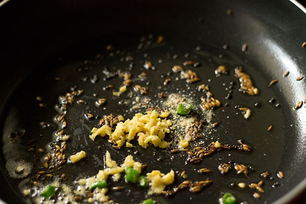 finely chopped ginger, finely chopped green chilies and asafoetida added to the pan for making sev tamatar sabji. 