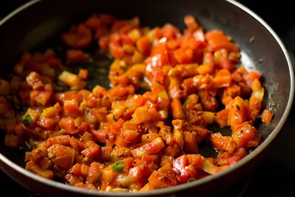 sautéing tomato mixture in the pan for making sev tamatar sabji. 