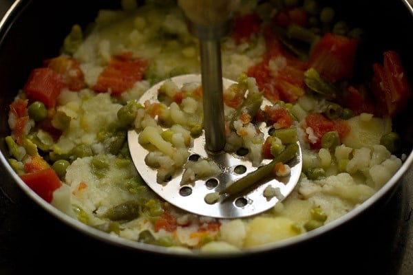 mashing vegetables with a potato mashed in a bowl