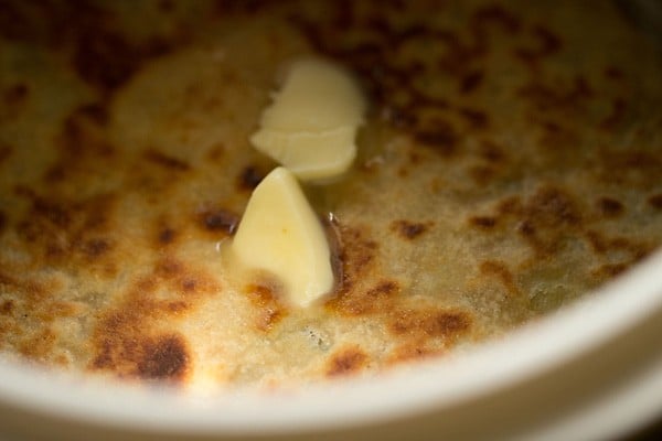 spreading butter on aloo kulchas