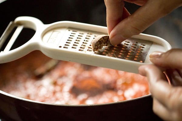 nutmeg being grated on a small grater above the pan. 