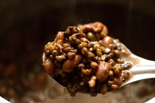 cooked urad dal and rajma in a spoon for dal makhani recipe. 