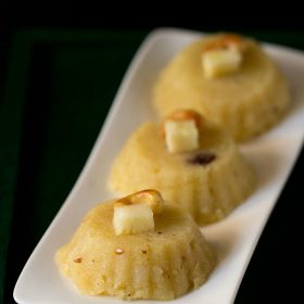 pineapple kesari garnished with fried cashew and pineapple cube and served on a white platter with text layover.