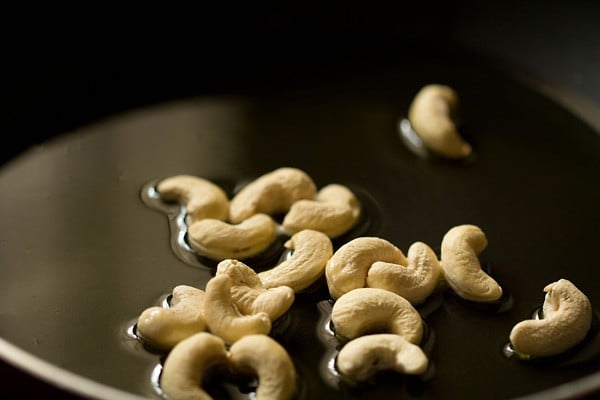 cashews added to hot ghee in pan. 