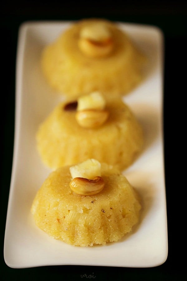 pineapple kesari garnished with fried cashew and pineapple cube and served on a white platter. 