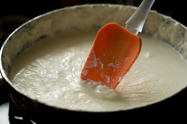 clotted cream layer being moved with orange spatula to make rabri recipe