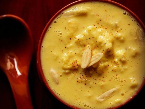 top shot of rabri in red bowl with nuts and a light sprinkle of saffron powder from top.