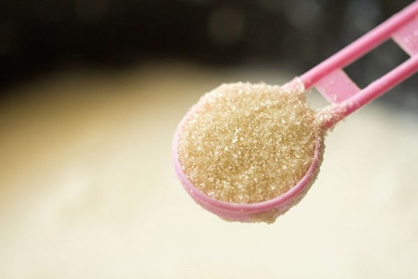 sugar being added to thickened milk for rasmalai recipe