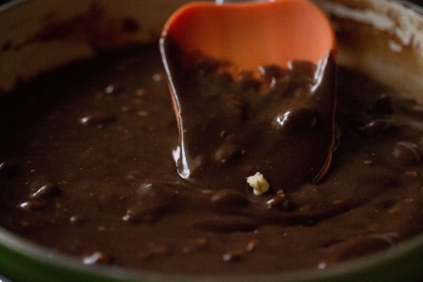 Mixing walnuts in the fudge mixture with an spatula.