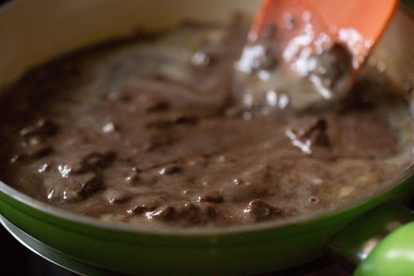 Stirring the melted chocolate fudge mixture constantly as it heats.