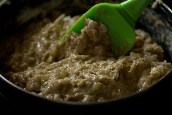 close up shot of green spatula mixing batter for eggless banana muffins