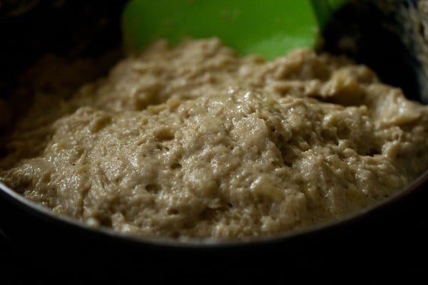 close up shot of green spatula mixing batter for eggless banana muffins