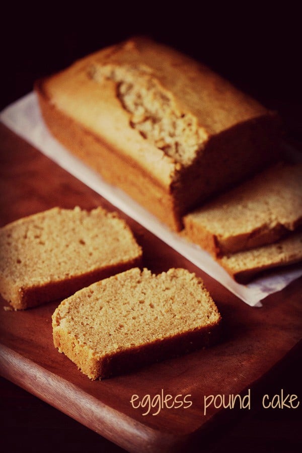 closeup shot of pound cake slice on a brown wooden board with pound cake loaf in the background