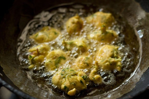 frying methi pakora in hot oil in kadai