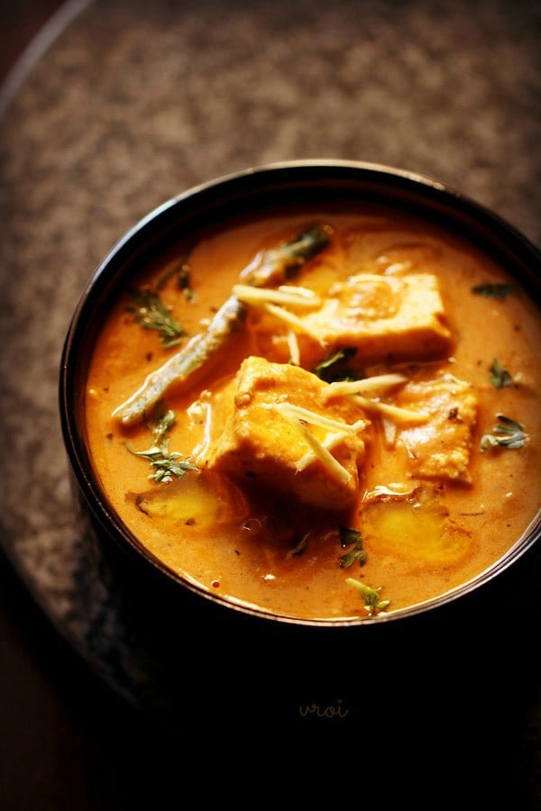 paneer lababdar served in a black bowl with ginger julienne on top