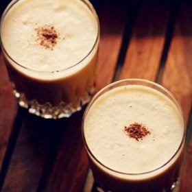 apple milkshake garnished with cinnamon powder and served in 2 glasses.