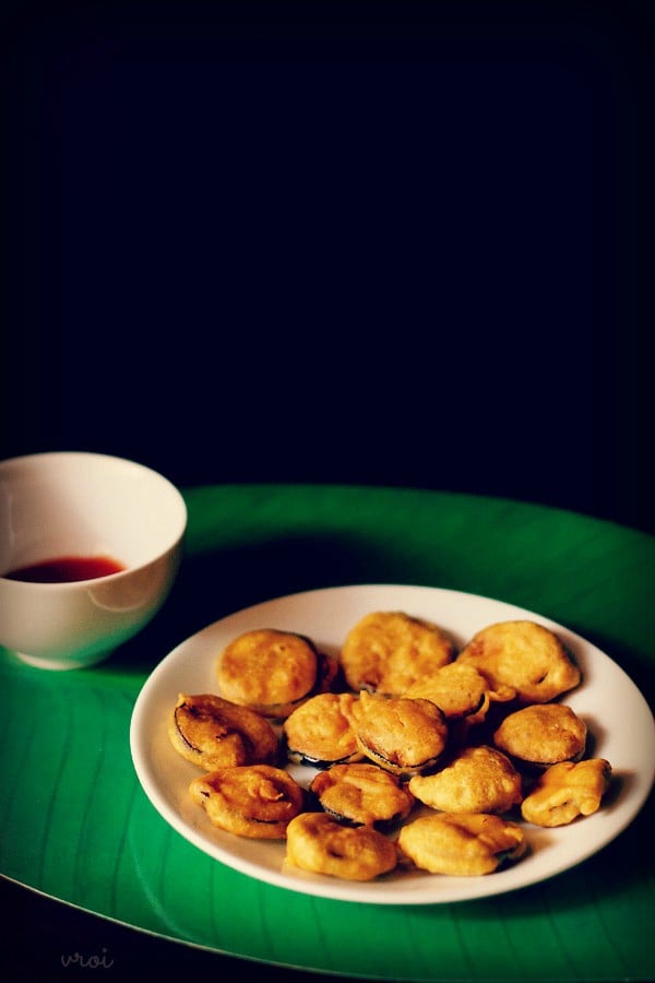 brinjal pakora served on a plate with a side of chutney in a bowl