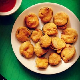 brinjal pakora or brinjal bajji on a white plate with a side of chutney at the side