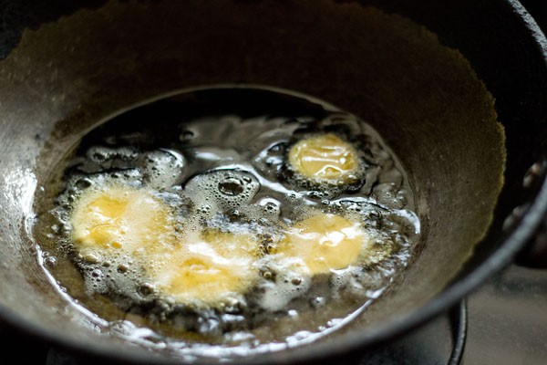 frying brinjal slices in hot oil in a kadai to make brinjal bajji