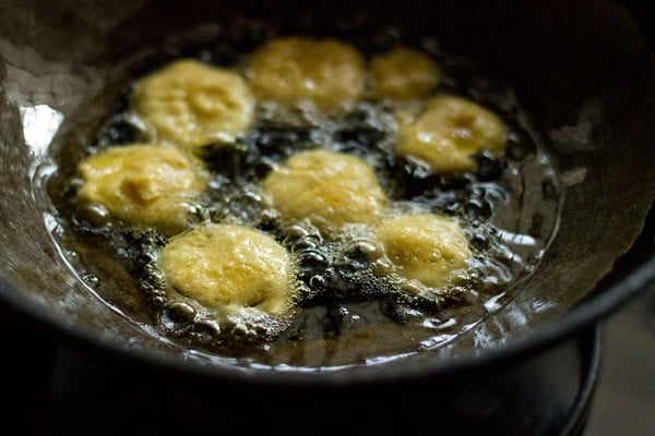 frying brinjal bajji in hot oil in a kadai