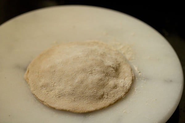 rolling cheese paratha and adding flour as needed
