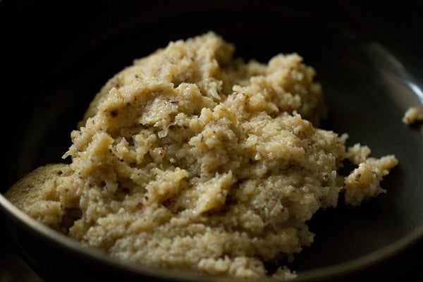 coconut ladoo mixture cooling in a black bowl