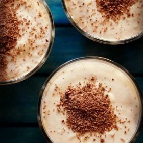 overhead shot of banana mousse garnished with grated chocolate and served in glass bowls with text layovers.