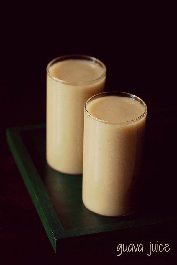 guava juice in two glasses on a dark green wooden tray