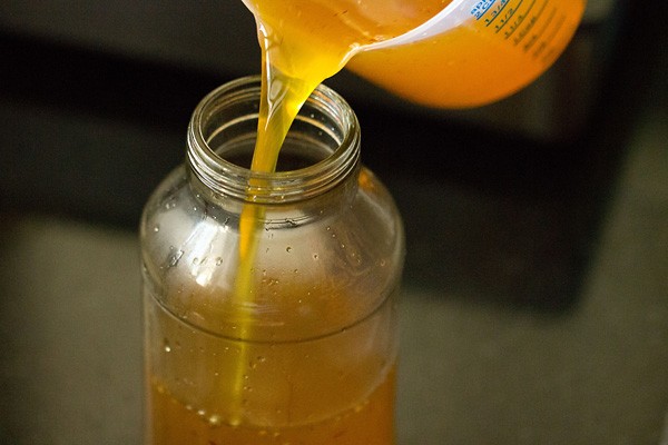 pouring lemon squash in sterilized glass bottle 